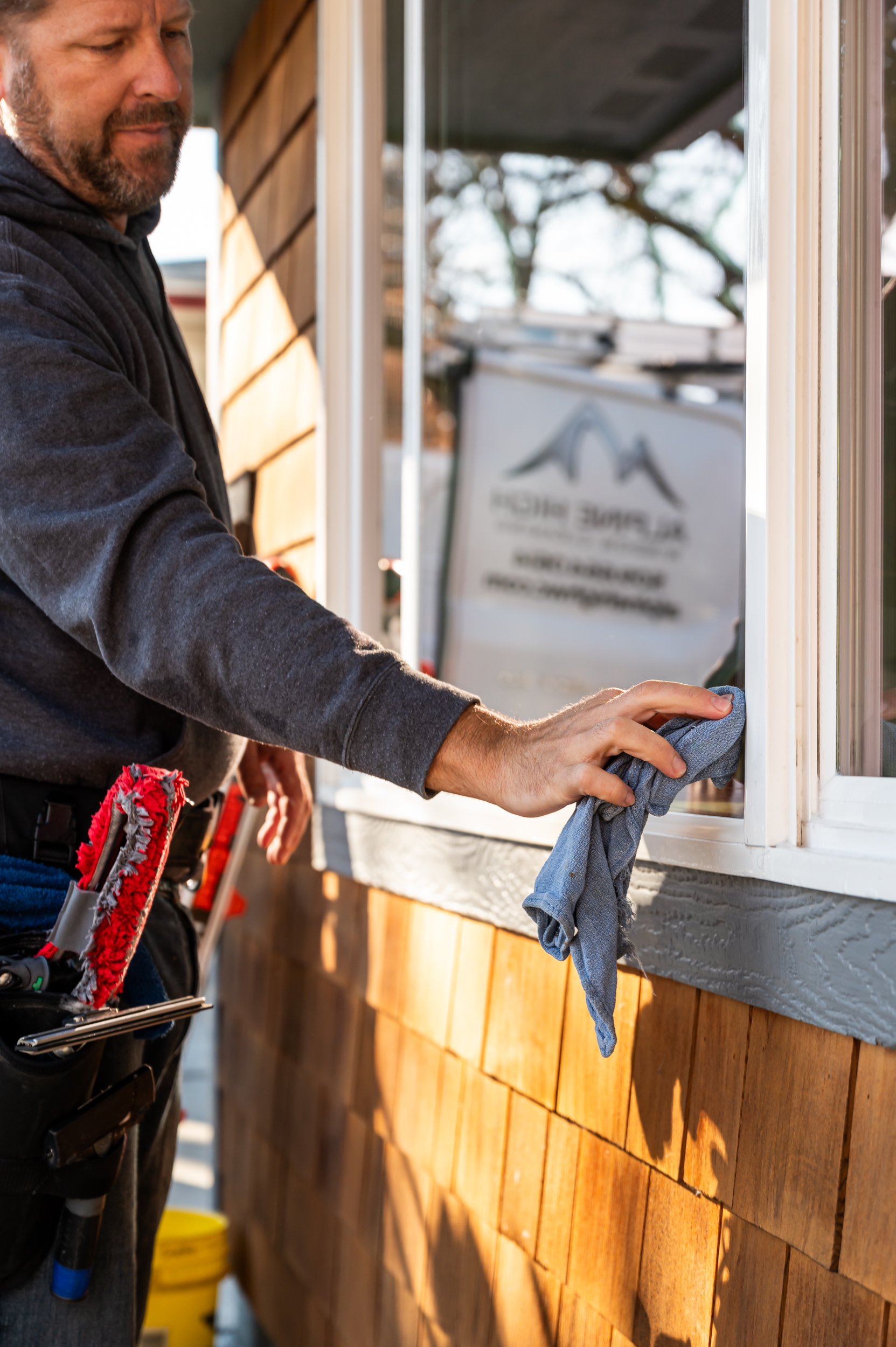 Detailing a window after being cleaned on a residence performed by Alpine High Window Cleaning